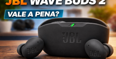 Fone de ouvido Bluetooth JBL Wave Buds 2 preto com estojo de carregamento sobre mesa de madeira, com texto “JBL Wave Buds 2 – Vale a Pena?”